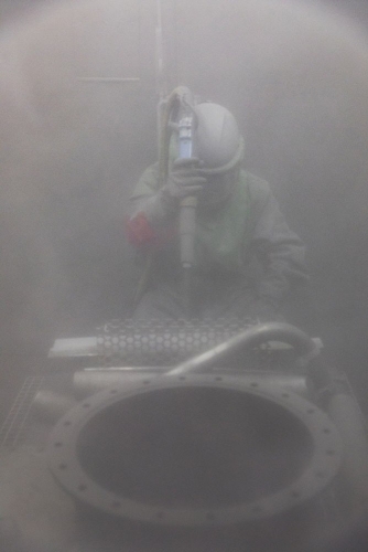 Opérateur effectuant un grenaillage de pièces en acier pour décontamination à la centrale nucléaire en démantèlement de Greifswald. | Philippe DUREUIL Photographie