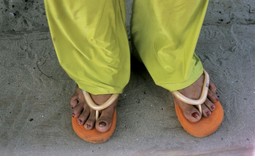 Pieds d'un homme aux ongles vernis en rouge portant des tongs orange et un pantalon vert fluo | Philippe DUREUIL Photographie