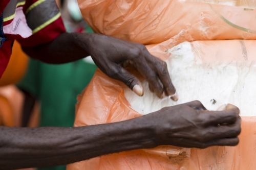 Photographique réalisée à Lomé pour le Groupe Necotrans. Un homme est au travail pour le contrôle qualité d'une Balle de coton. Agence de communication : Wellcom. | Philippe DUREUIL Photographie