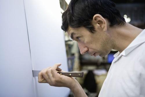 Portrait d'un opérateur au travail dans un atelier de fabrication de textiles techniques. Photo de reportage "men at work" réalisée pour le Groupe Serge Ferrari. Il contrôle la qualité sur une ligne de fabrication. | Philippe DUREUIL Photographie