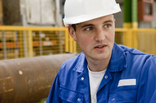 Portrait industriel d'un jeune ouvrier portant un casque dans une aciérie | Philippe DUREUIL Photographie