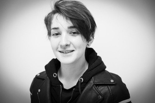 Portrait en noir et blanc d'une jeune femme souriante avec un effet de vignetage. Photo de portrait réalisée en reportage, lumière naturelle. | Philippe DUREUIL Photographie