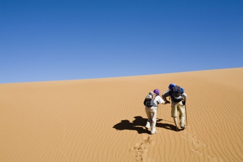 Couple de randonneurs qui monte sur une dune dans le désert | Philippe DUREUIL Photographie