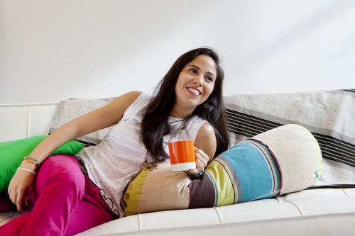Photo lifestyle d'une jeunne femme souriante et détendue sur un canapé. Vie quotidienne à la maison. | Philippe DUREUIL Photographie